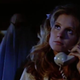 A blonde woman holds a telephone to her ear as a man dressed as a ghost approaches from behind.